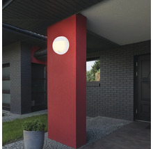 Un luminaire extérieur est monté sur un pilier devant une maison.
