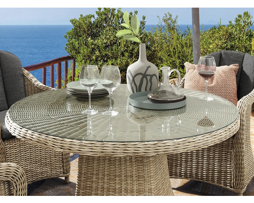 Scène de jardin avec table ronde en rotin et plateau en verre