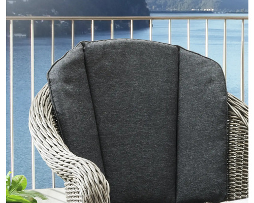 Gros plan d''un fauteuil en rotin avec coussins devant un paysage aquatique.