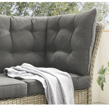 Detailansicht eines Rattansofas mit grauen Polstern und einer Decke