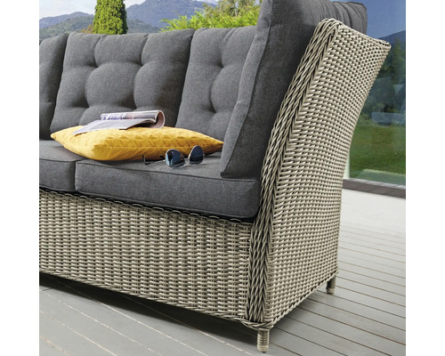 Canapé de jardin en rotin avec coussins gris, coussin jaune et lunettes de soleil