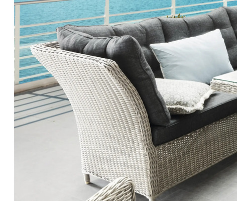 Gros plan d''un fauteuil en rotin avec rembourrage et coussins devant la mer.
