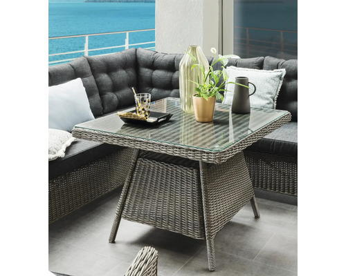 Quadratischer Gartentisch mit Glasplatte und Rattanstruktur neben Ecklounge