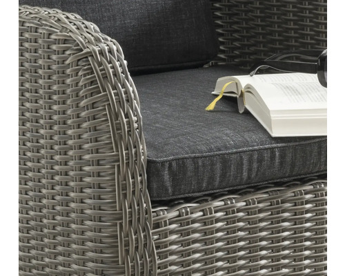 Detailansicht eines Korbsessels mit Kissen und Buch