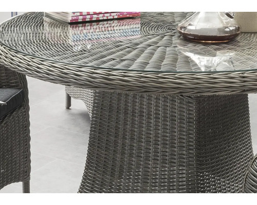 Vue détaillée d''une table de jardin ronde avec plateau en verre et tressage en rotin