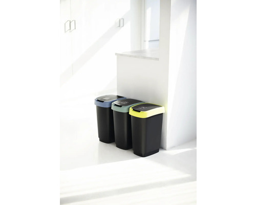 Trois poubelles noires avec couvercles colorés pour le tri des déchets dans une pièce lumineuse.