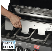 Un homme installe une plaque en acier inoxydable dans un barbecue à gaz.