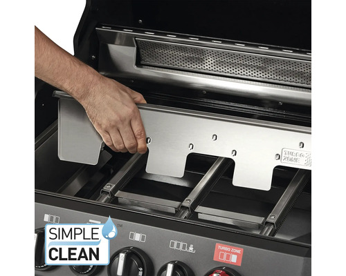 Une personne insère une plaque en acier inoxydable dans un gril.