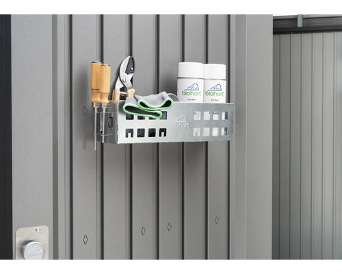 Regal mit Gartengeräten und Sprays an einer grauen Wand