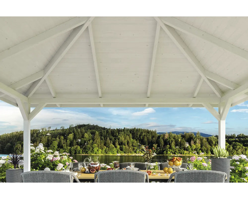 Weißer Holzpavillon mit Tisch und Stühlen im Freien mit Seeblick.