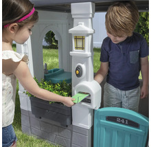 Des enfants jouent avec une cabane avec boîte aux lettres et évier