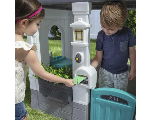 Des enfants jouent avec une cabane avec boîte aux lettres et évier