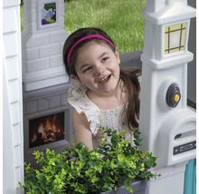 Fille dans une cabane de jeu avec boîte aux lettres, sonnette, cheminée et décoration de fenêtre