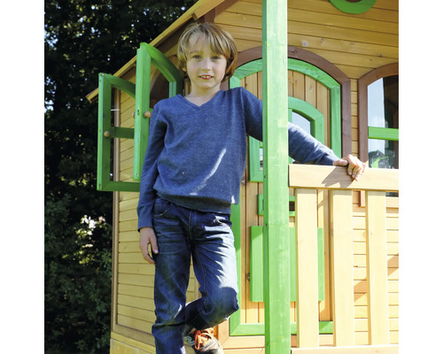 Enfant debout devant une cabane en bois dans le jardin