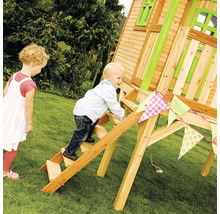 Un enfant grimpe sur une échelle en bois d''une cabane de jeu en bois dans le jardin