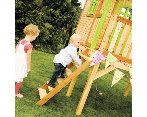 Kind klettert auf Holzleiter eines Holzspielhauses im Garten