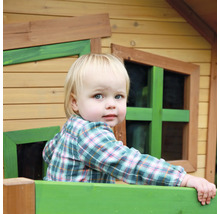 Ein Kind schaut aus einem Holzspielhaus