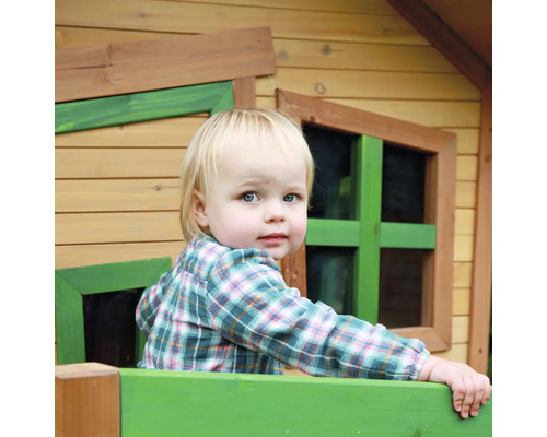 Ein Kind schaut aus einem Holzspielhaus