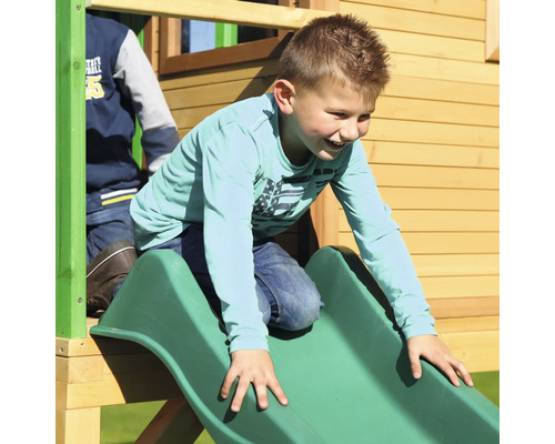 Garçon glissant sur un toboggan vert d''une tour de jeu