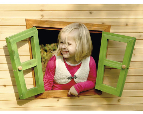 Mädchen schaut aus dem Fenster eines Holzspielhauses