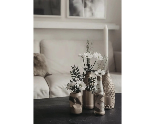 Dekorative Tischszene mit Blumen in Vasen vor einem Sofa