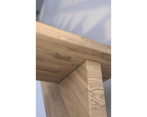 Vue détaillée d''une table en bois, mettant l''accent sur la connexion entre le plateau et les pieds.