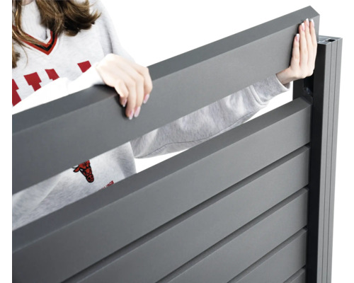 Frau montiert einen Sichtschutzzaun aus Aluminium.