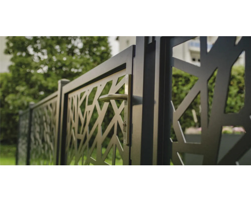 Metallzaun mit abstraktem Muster und Griff in einem Garten