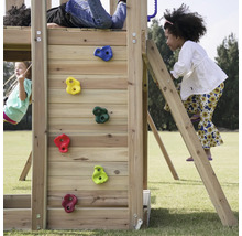 Kinder spielen auf einem Holzspielplatz mit Kletterwand, Leiter und Schaukel.