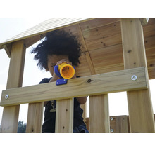 Un enfant joue avec un télescope jouet dans une cabane en bois