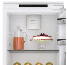 Intérieur d''un réfrigérateur avec un pichet de boisson, un gâteau et le système Haier Air Flow