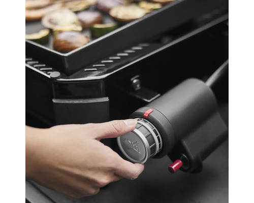 Gros plan d''un barbecue à gaz avec une main qui actionne le bouton de commande