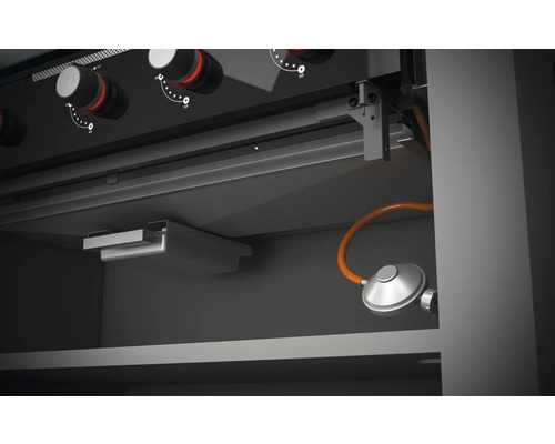 Vue intérieure d''un gril à gaz avec commandes et raccordement au gaz