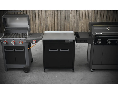 Drei Grillgeräte mit Stauraum im Freien vor einer Holzwand