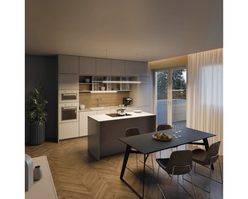 Cuisine moderne avec îlot de cuisine, table à manger et chaises dans une pièce lumineuse.