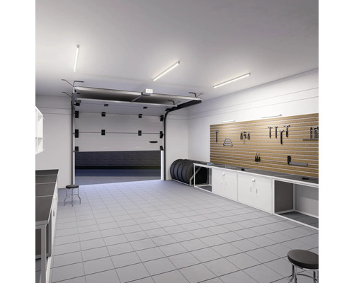 Garage avec établi, mur à outils, pneus et porte de garage ouverte