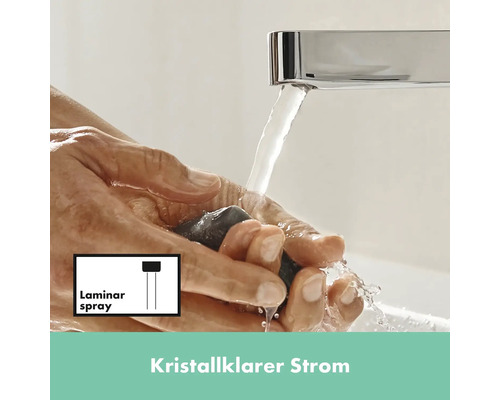 Eine Person hält einen Stein unter einen Wasserhahn mit Laminarstrahl.