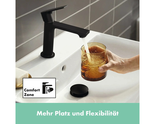 Schwarzer Waschtischmischer mit Wasserstrahl in einem Glas über einem Waschbecken, das mit dem Symbol Komfortzone gekennzeichnet ist.