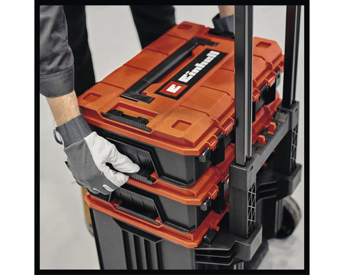 Einhell Werkzeugkoffer auf einem Rollwagen, mit Hand zum Öffnen eines Fachs.