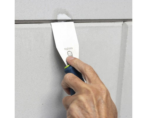 Ein Mann verwendet einen Spachtel, um eine Fuge zwischen zwei Paneelen zu versiegeln.