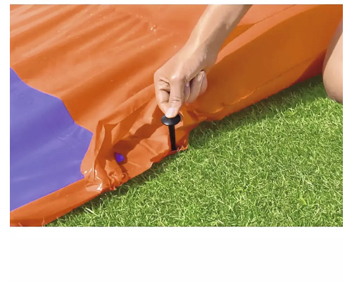 Une personne fixe le toboggan aquatique avec des piquets dans la pelouse