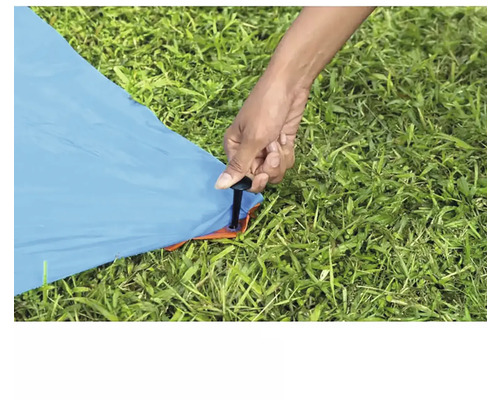 Une personne fixe une tente au sol avec un piquet.