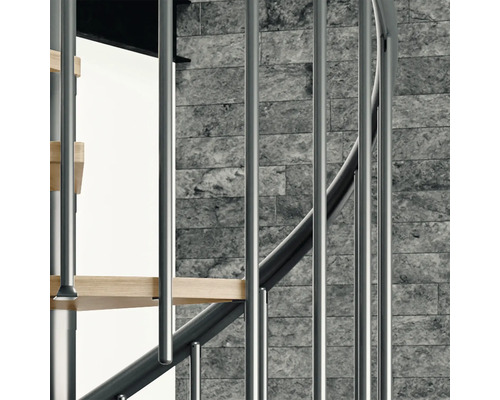 Detailansicht einer Wendeltreppe mit Metallgeländer und Holzstufen vor einer Steinwand.