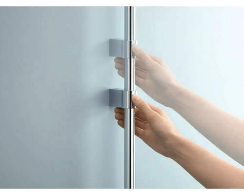 Une personne ajuste une barre de douche avec support mural.