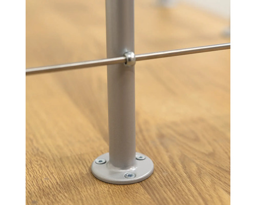 Detailansicht eines Geländerpfostens aus Metall, befestigt mit Schrauben auf einem Holzboden.
