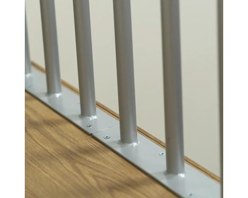 Detailansicht eines Treppengeländers mit Metallstäben und Bodenbefestigung.