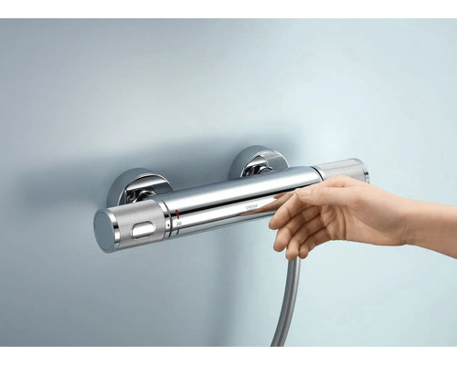 Aufputz-Thermostatbatterie mit Hand darunter an der Wand