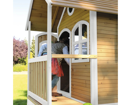 Kind betritt ein Holzspielhaus mit Fenstern und Veranda