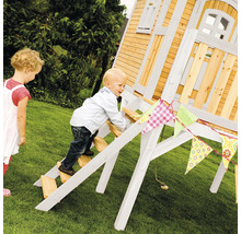 Kind klettert auf ein Holzspielhaus im Garten, dekoriert mit einer bunten Wimpelkette.