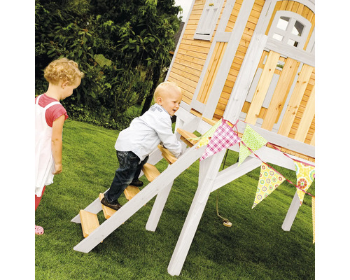 Kinderspielhaus mit Leiter und Dekoration im Garten mit zwei Kindern
